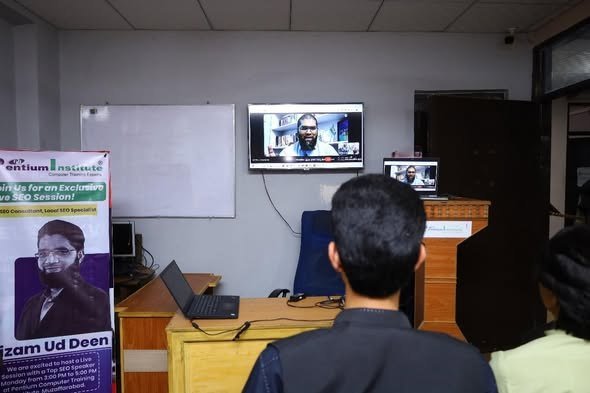 Students watching the live SEO session at Pentium Computer Training Institute, with the promotional banner naming Nizam Ud Deen