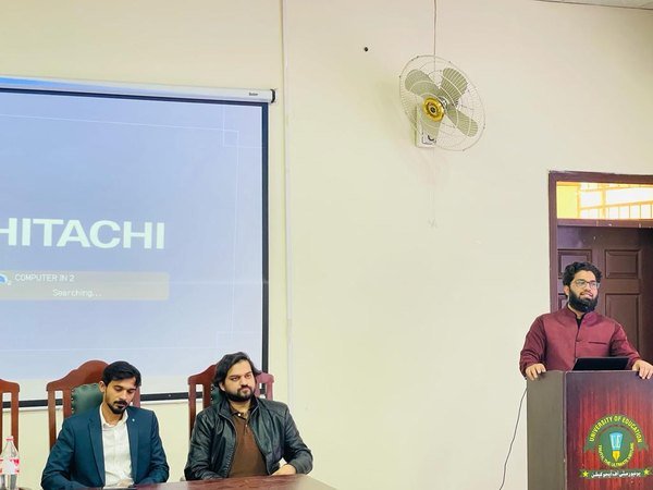 Nizam Ud Deen speaking from a University of Education lectern at an orientation session in Multan
